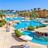 Słoneczny dzień w Stella Beach Resort & Spa Makadi Bay. Goście relaksują się przy basenach, pod palmami i parasolami.