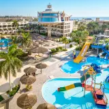 Resort Seagull z basenami i zjeżdżalniami wodnymi, otoczony palmami i budynkami hotelowymi, blisko morza.