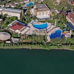 Widok z lotu ptaka na kompleks hotelowy Marvida Family Eco nad jeziorem, z basenami, zjeżdżalniami i terenami zielonymi.