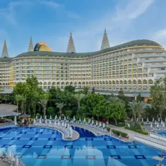 Luksusowy hotel Delphin Imperial Lara z basenem i leżakami, otoczony zielenią.