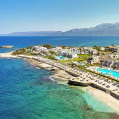 Luksusowy Aldemar Knossos Royal na Krecie, z białymi budynkami, basenami i plażą nad turkusowym morzem.