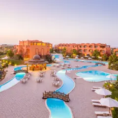 Dream Lagoon & Aqua Park Resort: malowniczy widok na kompleks basenów i budynków w ciepłych barwach, z mostkami i leżakami.