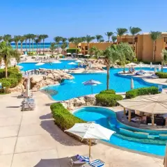 Słoneczny dzień w Stella Beach Resort & Spa Makadi Bay. Goście relaksują się przy basenach, pod palmami i parasolami.