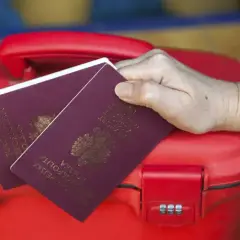 Dwa paszporty na czerwonej walizce. Zastanawiasz się, paszport dla dziecka ile ważny?