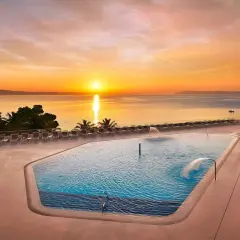 Zachód słońca nad basenem w Medora Auri Family Beach Resort. Woda w basenie lśni, a leżaki czekają na gości.