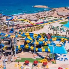 Wodne zjeżdżalnie w Blend Club Aqua Resort kuszą kolorami i zabawą. Widać plażę i turkusowe morze.