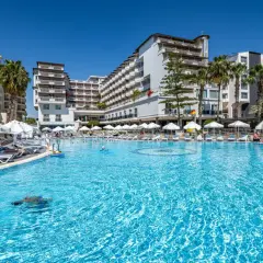 Basen hotelowy Granada Luxury Okurcalar, z leżakami, parasolami i palmami. Dzieci pluskają się w wodzie.