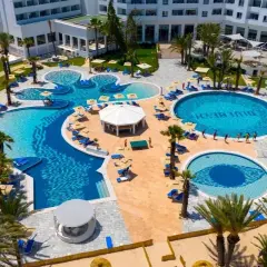 Luksusowy kompleks basenów z palmami i leżakami, z napisem "Blue Beach" w wodzie. Idealne miejsce na wakacje w Monastyrze.