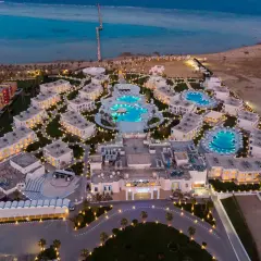 Widok z lotu ptaka na luksusowy resort Casa Blue, z basenami, budynkami i morzem w tle, oświetlony wieczorem.