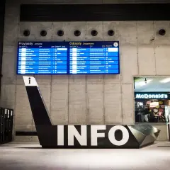 Nowoczesny dworzec w Katowicach z tablicami odjazdów i przyjazdów, futurystycznym napisem INFO i McDonald's. Nietypowe atrakcje Katowice czekają!