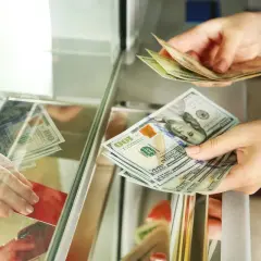 Wymiana pieniędzy w Tunezji: euro czy dolary? Dłonie przekazują sobie banknoty 100 dolarów.