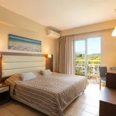 Przytulny pokój w Mitsis Messonghi Beach z widokiem na zieleń. Duże łóżko, klimatyzacja i balkon zapraszają do relaksu.