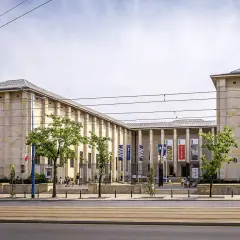 Muzeum Narodowe w Warszawie – jedno z kluczowych warszawa miejsca do zwiedzania. Monumentalna budowla z flagami i drzewami przed wejściem.