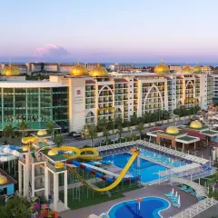 Luksusowy Alan Xafira Deluxe Resort & Spa z basenami i zjeżdżalniami, w blasku zachodzącego słońca.