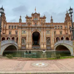 Majestatyczny plac hiszpański w Sewilli z kanałem i łódkami. Architektura zachwyca detalami.