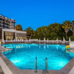 Basen z niebieskim podświetleniem i zjeżdżalnią wodną w Seaphoria Beach Resort. Leżaki i palmy tworzą wakacyjny klimat.