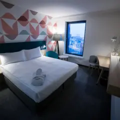 Przytulny pokój hotelowy z łóżkiem, szlafrokiem i widokiem na miasto. "Room only" to oferta bez wyżywienia.
