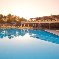 Basen w club mermaid village, z leżakami i zjeżdżalniami, w blasku zachodzącego słońca.