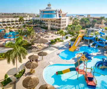 Resort Seagull z basenami i zjeżdżalniami wodnymi, otoczony palmami i budynkami hotelowymi, blisko morza.