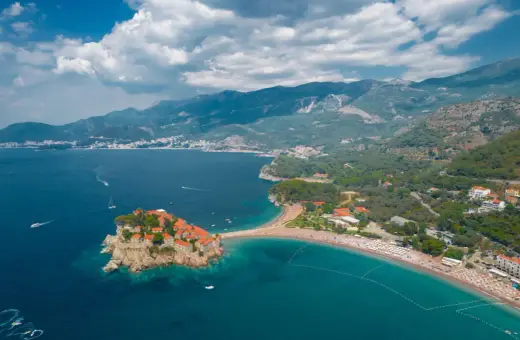Sveti Stefan, Czarnogóra, idealna pogoda we wrześniu. Wyspa z kamiennymi domkami i plaża z turkusową wodą.