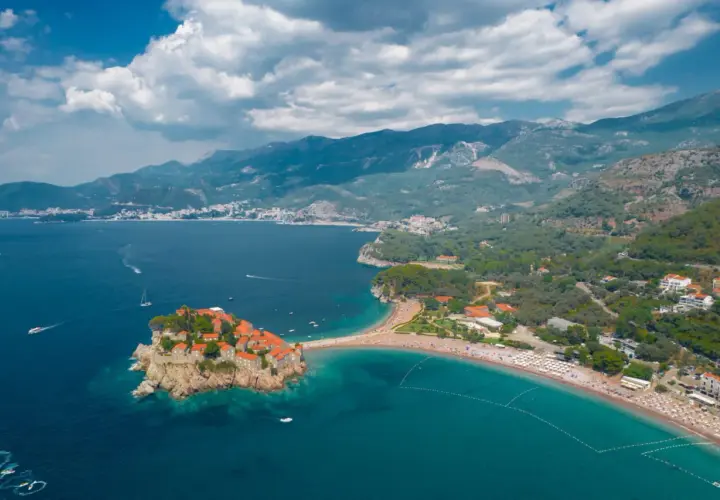 Sveti Stefan, Czarnogóra, idealna pogoda we wrześniu. Wyspa z kamiennymi domkami i plaża z turkusową wodą.