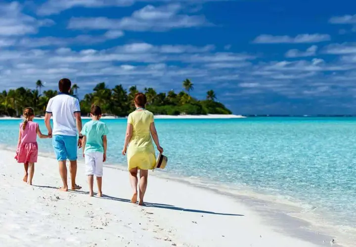 Rodzina spaceruje po rajskiej plaży. Idealne wakacje z dziećmi gdzie? Na pewno tutaj!