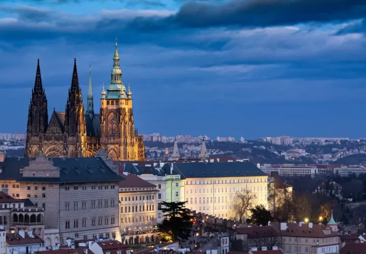 Imponujący zamek w Pradze o zmierzchu, z majestatyczną katedrą i oświetlonymi budynkami na pierwszym planie.