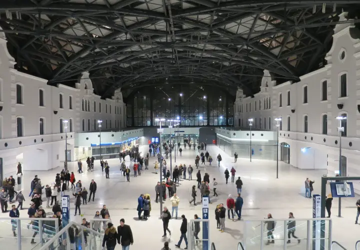 Nowoczesny dworzec Łódź Fabryczna, idealny punkt startowy, by zobaczyć co warto zobaczyć w Łodzi w jeden dzień. Tłumy podróżnych pod imponującym dachem.