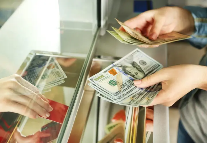 Wymiana pieniędzy w Tunezji: euro czy dolary? Dłonie przekazują sobie banknoty 100 dolarów.