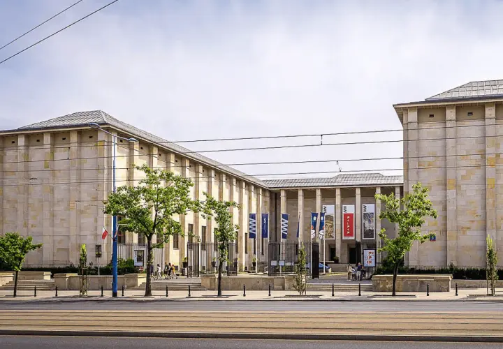 Muzeum Narodowe w Warszawie – jedno z kluczowych warszawa miejsca do zwiedzania. Monumentalna budowla z flagami i drzewami przed wejściem.