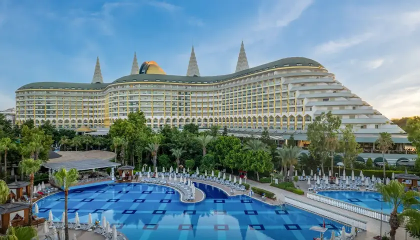 Luksusowy hotel Delphin Imperial Lara z basenem i leżakami, otoczony zielenią.