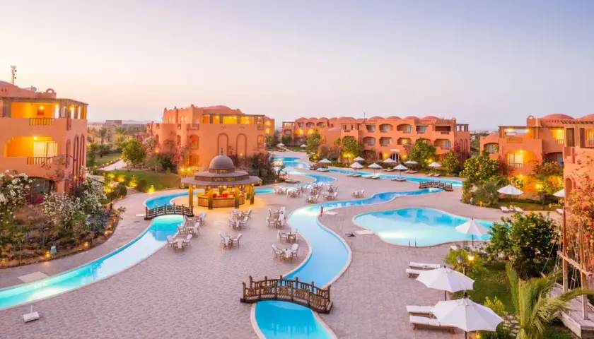 Dream Lagoon & Aqua Park Resort: malowniczy widok na kompleks basenów i budynków w ciepłych barwach, z mostkami i leżakami.