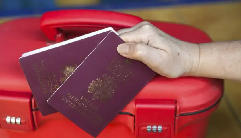 Dwa paszporty na czerwonej walizce. Zastanawiasz się, paszport dla dziecka ile ważny?