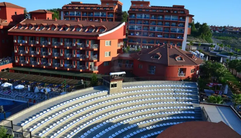 Amfiteatr z białymi siedzeniami i hotelami w tle, idealne miejsce na wieczorne pokazy w club side coast.