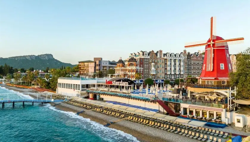 Wyjątkowy Greenwood Kemer Resort z holenderskim wiatrakiem i budynkami w stylu Amsterdamu nad turkusowym morzem.
