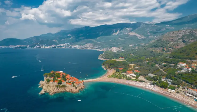Sveti Stefan, Czarnogóra, idealna pogoda we wrześniu. Wyspa z kamiennymi domkami i plaża z turkusową wodą.