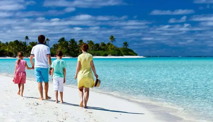 Rodzina spaceruje po rajskiej plaży. Idealne wakacje z dziećmi gdzie? Na pewno tutaj!