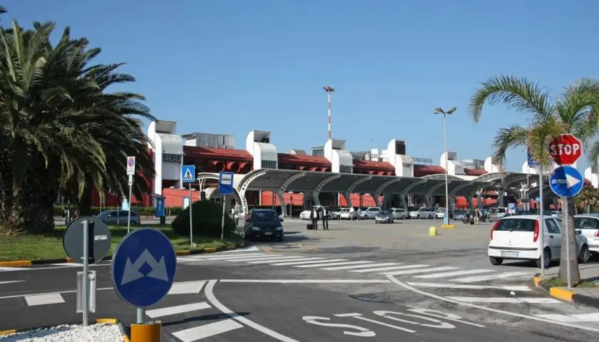 Lamezia Terme lotnisko, z palmami i samochodami przed nowoczesnym budynkiem terminalu.