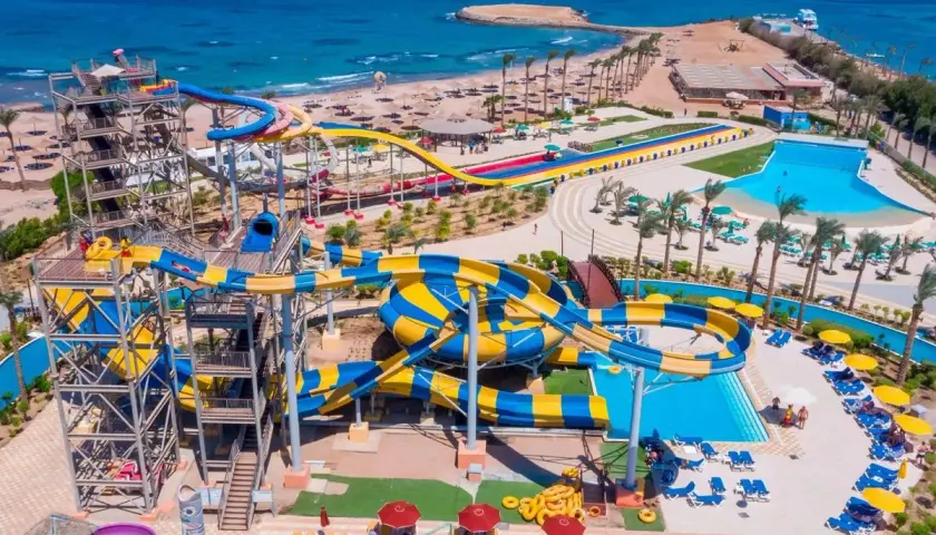 Wodne zjeżdżalnie w Blend Club Aqua Resort kuszą kolorami i zabawą. Widać plażę i turkusowe morze.