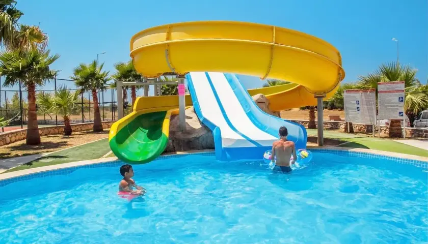 Dzieci bawią się w basenie przy zjeżdżalniach wodnych w **garden of sun spa & wellness**.