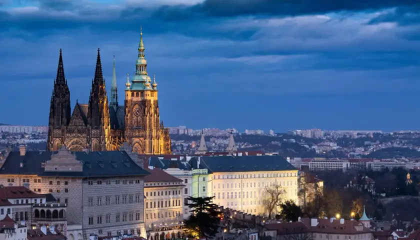 Imponujący zamek w Pradze o zmierzchu, z majestatyczną katedrą i oświetlonymi budynkami na pierwszym planie.