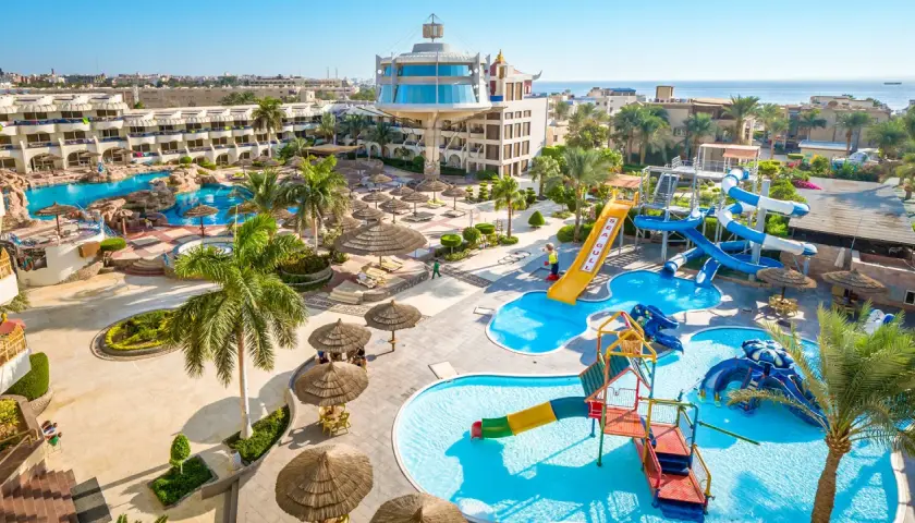 Resort Seagull z basenami i zjeżdżalniami wodnymi, otoczony palmami i budynkami hotelowymi, blisko morza.
