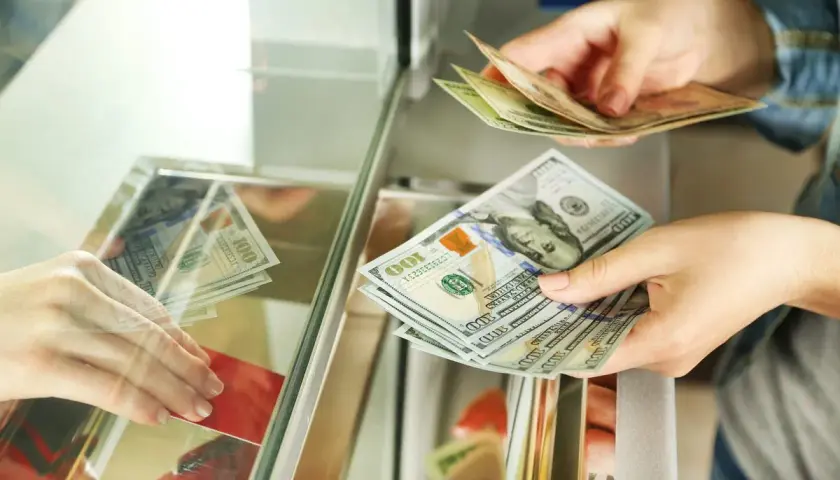 Wymiana pieniędzy w Tunezji: euro czy dolary? Dłonie przekazują sobie banknoty 100 dolarów.
