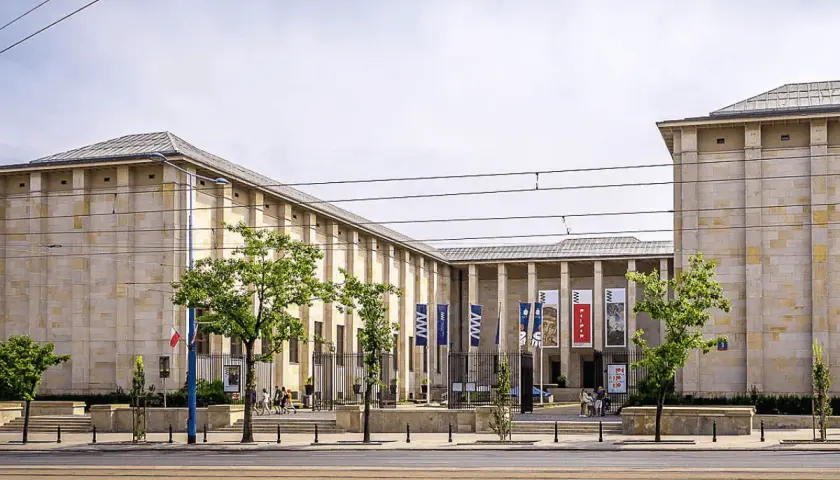 Muzeum Narodowe w Warszawie – jedno z kluczowych warszawa miejsca do zwiedzania. Monumentalna budowla z flagami i drzewami przed wejściem.