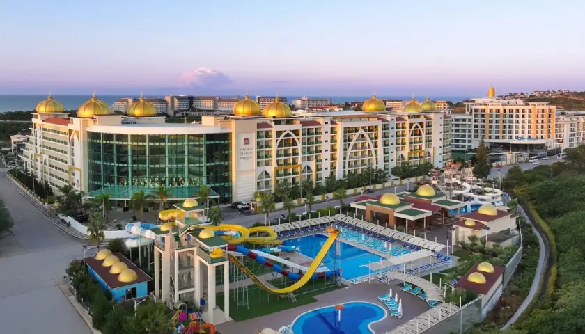 Luksusowy Alan Xafira Deluxe Resort & Spa z basenami i zjeżdżalniami, w blasku zachodzącego słońca.