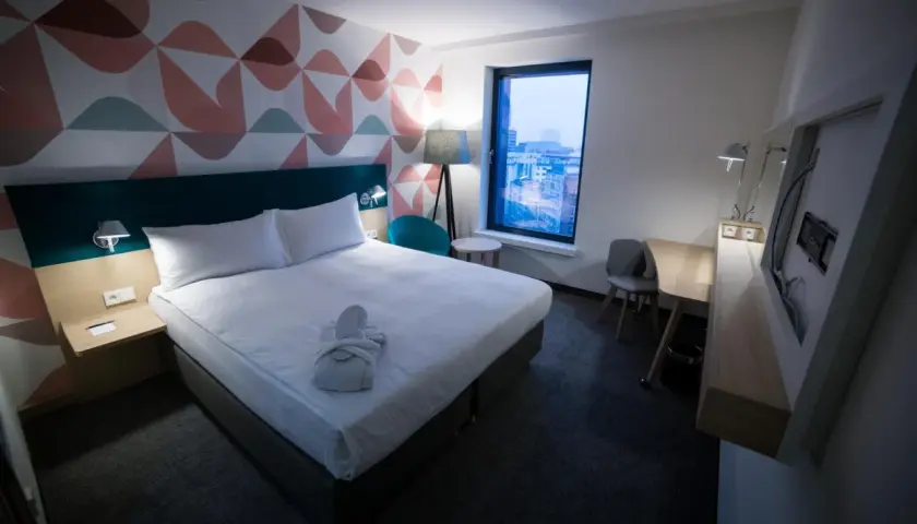 Przytulny pokój hotelowy z łóżkiem, szlafrokiem i widokiem na miasto. "Room only" to oferta bez wyżywienia.