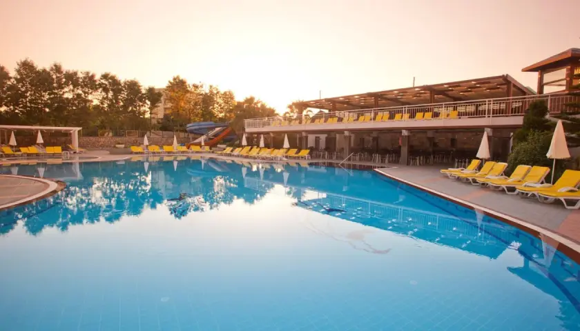 Basen w club mermaid village, z leżakami i zjeżdżalniami, w blasku zachodzącego słońca.