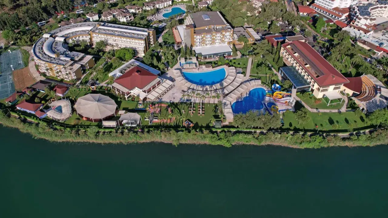 Widok z lotu ptaka na kompleks hotelowy Marvida Family Eco nad jeziorem, z basenami, zjeżdżalniami i terenami zielonymi.