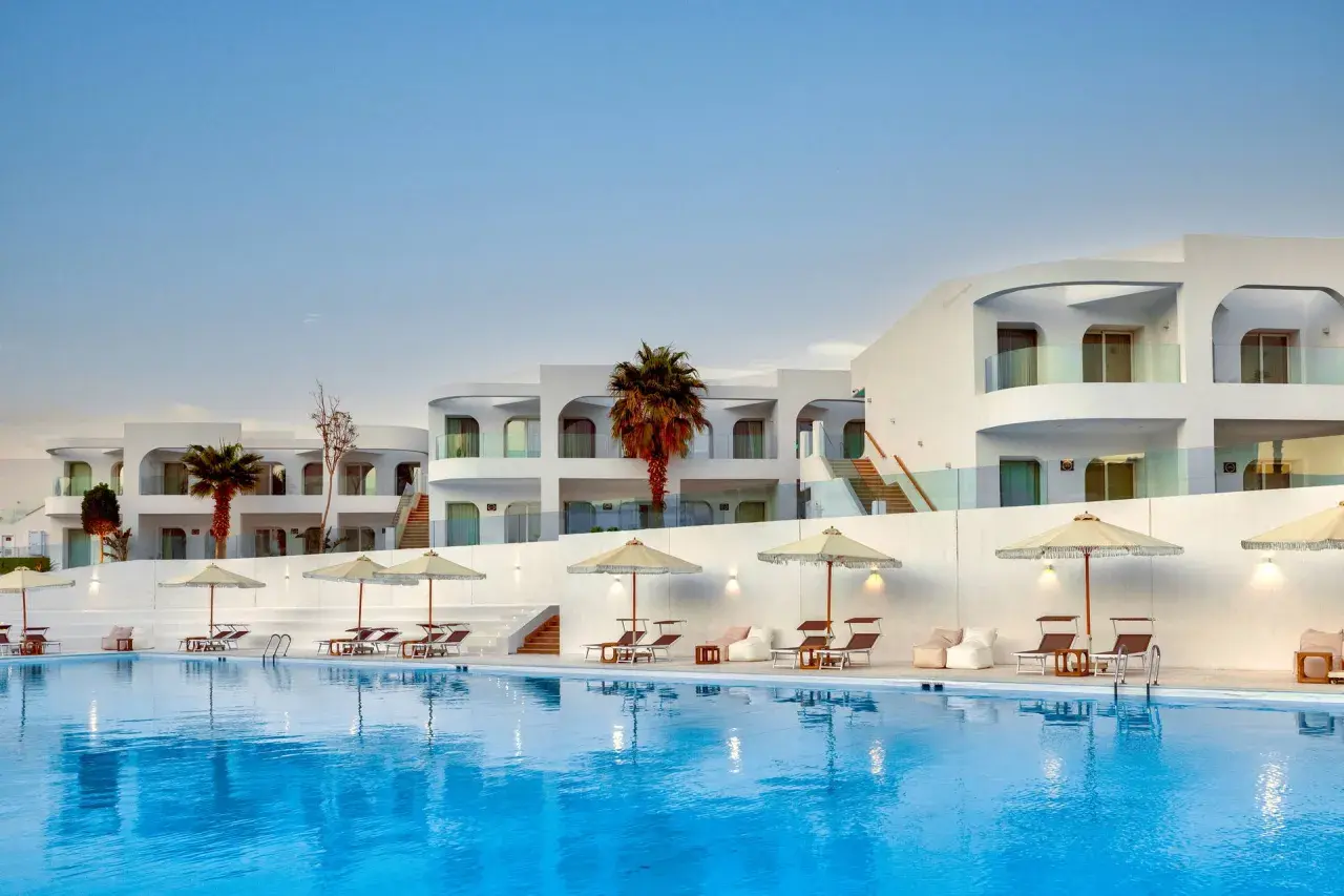 Basen i białe budynki z palmami w Meraki Resort Sharm El Sheikh. Idealne miejsce na relaks.