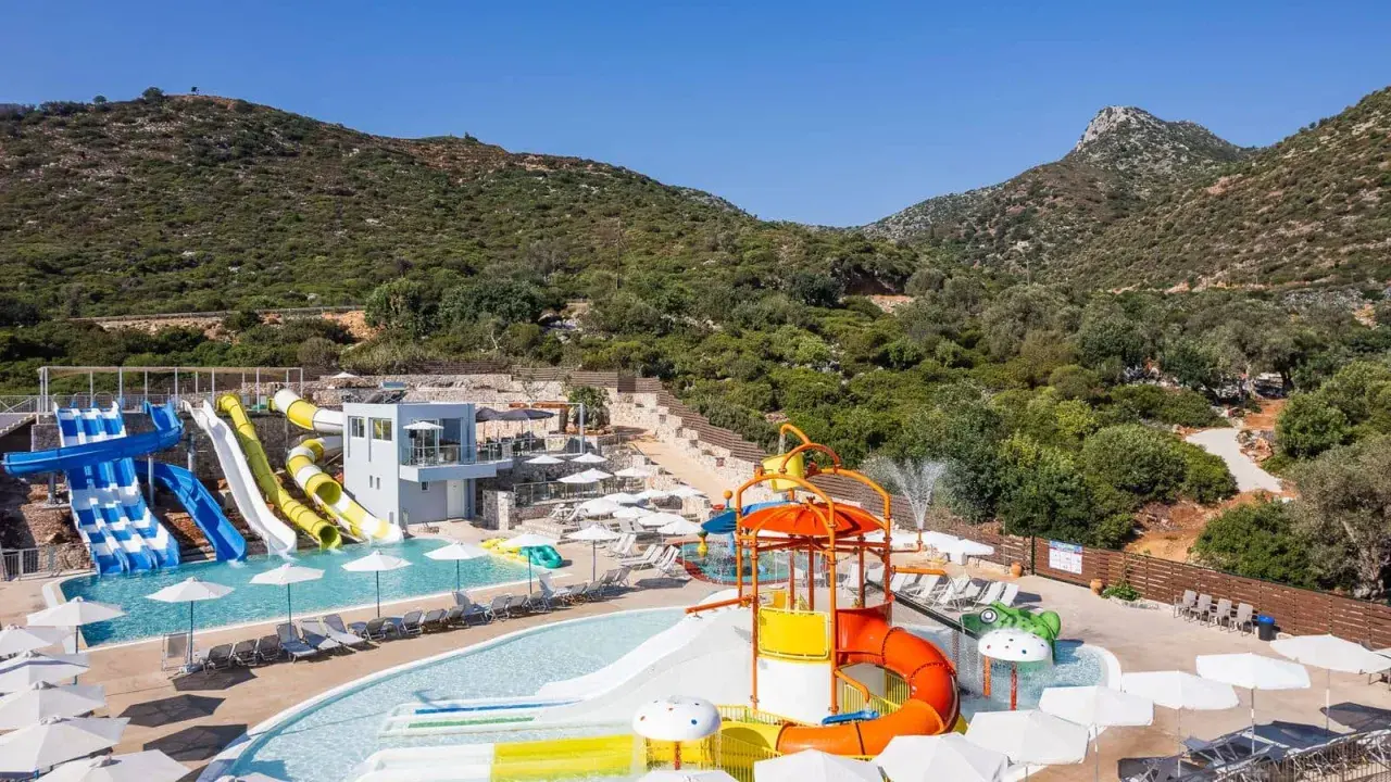 Atali Grand Resort: kolorowy aquapark z licznymi zjeżdżalniami i basenami, otoczony zielonymi wzgórzami.